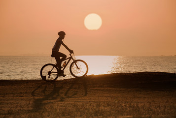 Naklejka na ściany i meble silhouette of cyclist on sunset or sunrise sky background