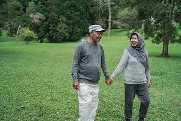 Naklejka premium portrait of asian muslim senior couple walking in the garden together
