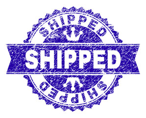 SHIPPED rosette seal watermark with distress style. Designed with round rosette, ribbon and small crowns. Blue vector rubber watermark of SHIPPED caption with dust style.