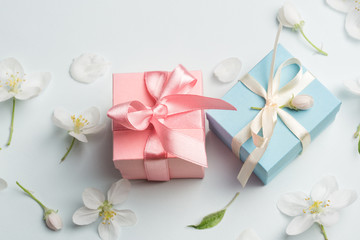 two gifts surrounded by Apple white flowers. blue and pink presents. pretty background top view,