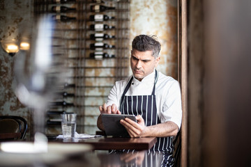 Male chef working on digital tablet in restaurant