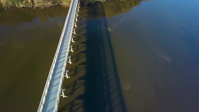 Spectacular slow reveal aerial drone shot of boardwalk on a lake in Oso Flaco, located on the Central Coast of California, Santa Barbara County