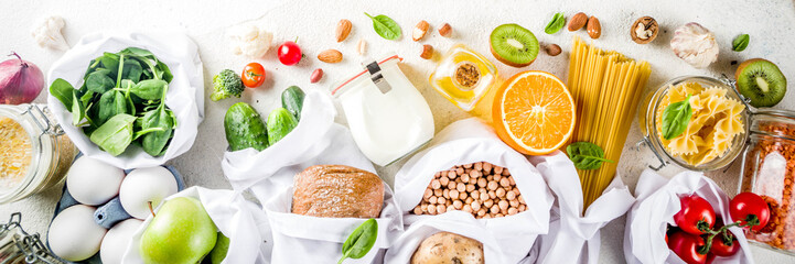 Zero waste shopping and sustanable lifestyle concept, various farm organic vegetables, grains, pasta, eggs and fruits in reusable packaging supermarket bags. copy space top view, banner