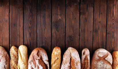 Assortment of baked bread and bread rolls on wooden table background
