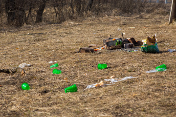 Close-up scattered garbage and lots plastic cups on spring grass left by tourists in mountains in...