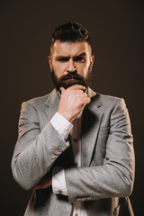 handsome beard businessman thinking and looking at camera isolated on brown