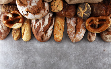 Assortment of baked bread and bread rolls on stone table background
