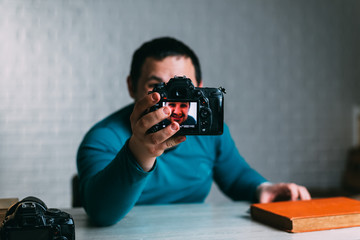 a man with a beard takes a selfie on a large SLR camera