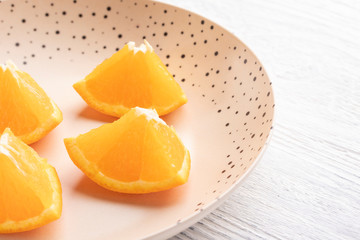 Freshly sliced oranges on a dotted brown plate.