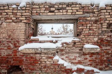 View of the temple through a window in the ruined wall. Russia, the city of Torzhok