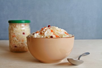 Fermented vegetables cabbage with carrot and cranberry in bowl with  glass jar background