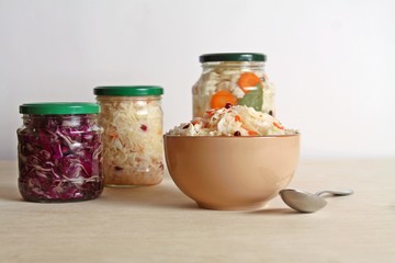 Fermented vegetables cabbage with carrot and cranberry in bowl with cauliflower and red cabbage in glass jar background