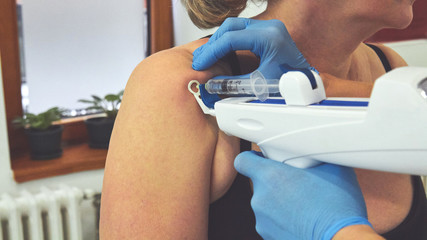 Female doctor doing mesotherapy treatment for shoulder pain. Beauty and healthcare.