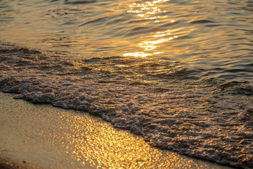 Close up of sea wave with sunset or sunrise beach and sand background