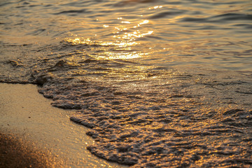 Close up of sea wave with sunset or sunrise beach and sand background
