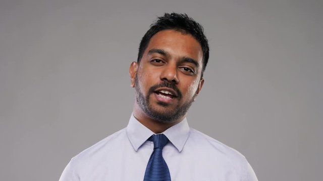 business, communication and people concept - indian businessman having video conference or interview and talking over grey background