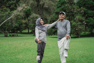 two senior man and woman doing some stretching in nature park together. old people healthcare by...