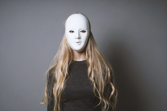 mysterious woman hiding face and identity behind plain white mask - lack of emotion concept