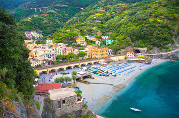 Top aerial view of green hill, railway, beach and harbor of Monterosso town village at sunset dusk, Genoa Gulf, Ligurian Sea, National park Cinque Terre, La Spezia, Liguria, Italy