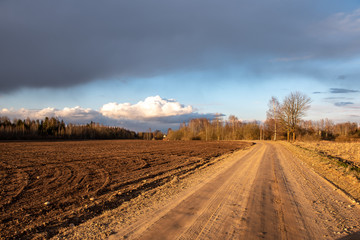 Fototapeta na wymiar empty country gravel road with mud puddles and bumps