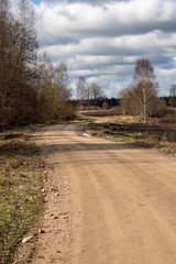 empty country gravel road with mud puddles and bumps