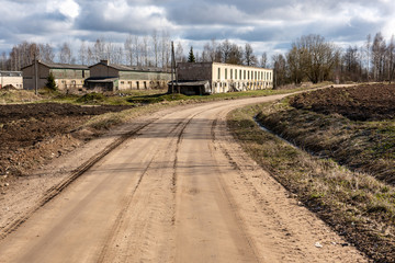 empty country gravel road with mud puddles and bumps