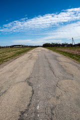 empty country gravel road with mud puddles and bumps