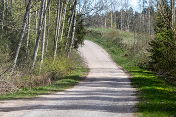 empty country gravel road with mud puddles and bumps