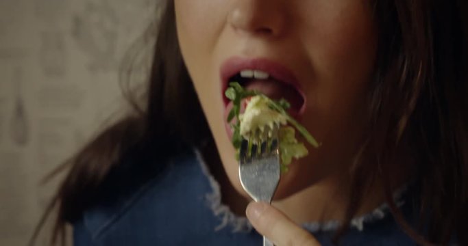 An attractive, young woman enjoys eating a healthy sandwich and salad for lunch.  Shot in slow motion