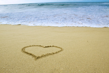 photo of simply heart shape drawn on sand on the beach by the ocean