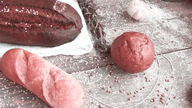 Different types of bread on wooden table dusted with flour. Slow pan.	Concept of natural food and organic food.