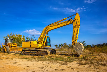 Day view of yellow bulldozer and excavator with a shovel after work.