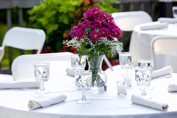 Purple bouquet of flowers on a table in clear jars of water during a wedding celebration 