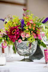 Pink and red and green bouquet of flowers on a table in a jar during a wedding celebration 