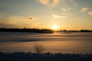 colorful sunset in winter over countryside fields covered in snow
