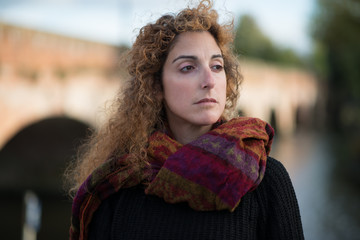 portrait of noble and proud beautiful woman with long red windswept curly hair and brown eyes on...