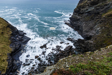 Obraz premium view from the top of the hill, the rocky coastline and the white water foam, the rocky mountains off the coast and the horizon