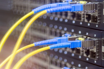 Two pairs of fiber optic patch cords are connected to a manageable Internet switch. Server hardware datacenter. The concept of high-speed data transfer and modern Internet technologies. 