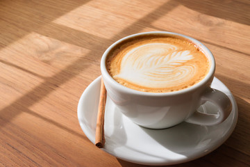A Cup of hot latte art coffee on wooden table with book in coffee shop cafe.