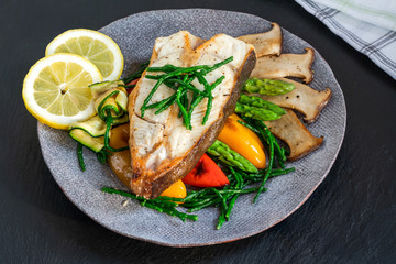 Grilled halibut steak with vegetables - sweet mini peppers, courgette, asparagus and oyster mushrooms, garnished with samphire