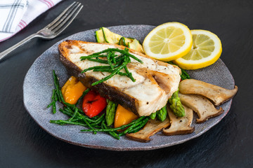 Grilled halibut steak with vegetables - sweet mini peppers, courgette, asparagus and oyster mushrooms, garnished with samphire