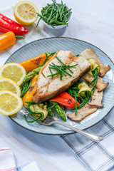 Grilled halibut steak with vegetables - sweet mini peppers, courgette, asparagus and oyster mushrooms, garnished with samphire