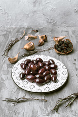 decorated porcelain plates with green and black olives, in gray rustic setting