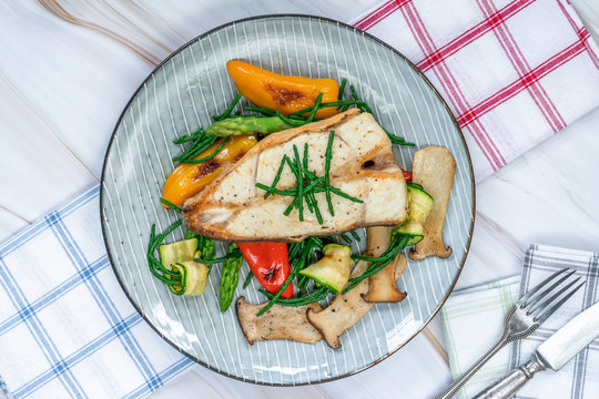 Grilled halibut steak with vegetables - sweet mini peppers, courgette, asparagus and oyster mushrooms, garnished with samphire