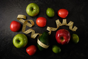 Healthy food. Vegetables and fruits. Measuring tape. On a black background. Top view.