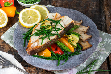 Grilled halibut steak with vegetables - sweet mini peppers, courgette, asparagus and oyster mushrooms, garnished with samphire