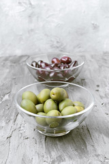 glass bowls with green and black olives, on gray rustic stage