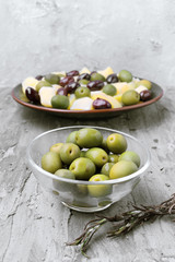 glass bowls with green and black olives, on gray rustic stage