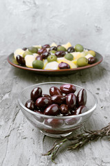 glass bowls with green and black olives, on gray rustic stage