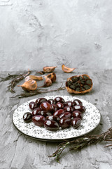 decorated porcelain plates with green and black olives, in gray rustic setting